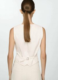 Top sans manches beige clair au design ajusté, avec un détail de boucle à l'arrière et une texture de tissu lisse.