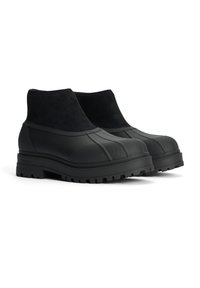 Mustat nilkkurit, joissa on kuminen alaosa urilla ja mokkanahkainen päällinen. Paksu, teksturoidulla pohjalla varustettu pohja takaa pidon. Yksinkertainen ja toiminnallinen muotoilu.