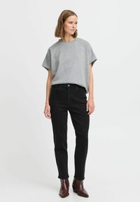 Sivi kratki rukav T-shirt s opuštenim krojem uparen s crnim uskim trapericama i smeškim čizmama do gležnja. Jednostavan dizajn s neutralnim bojama i suptilnom teksturom.