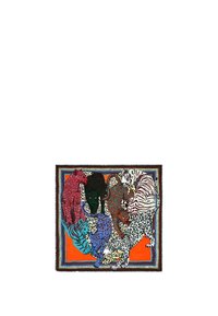 Pañuelo de seda con estampados de animales coloridos, incluyendo tigres y leopardos, sobre un fondo naranja. Acabado con un borde decorativo.