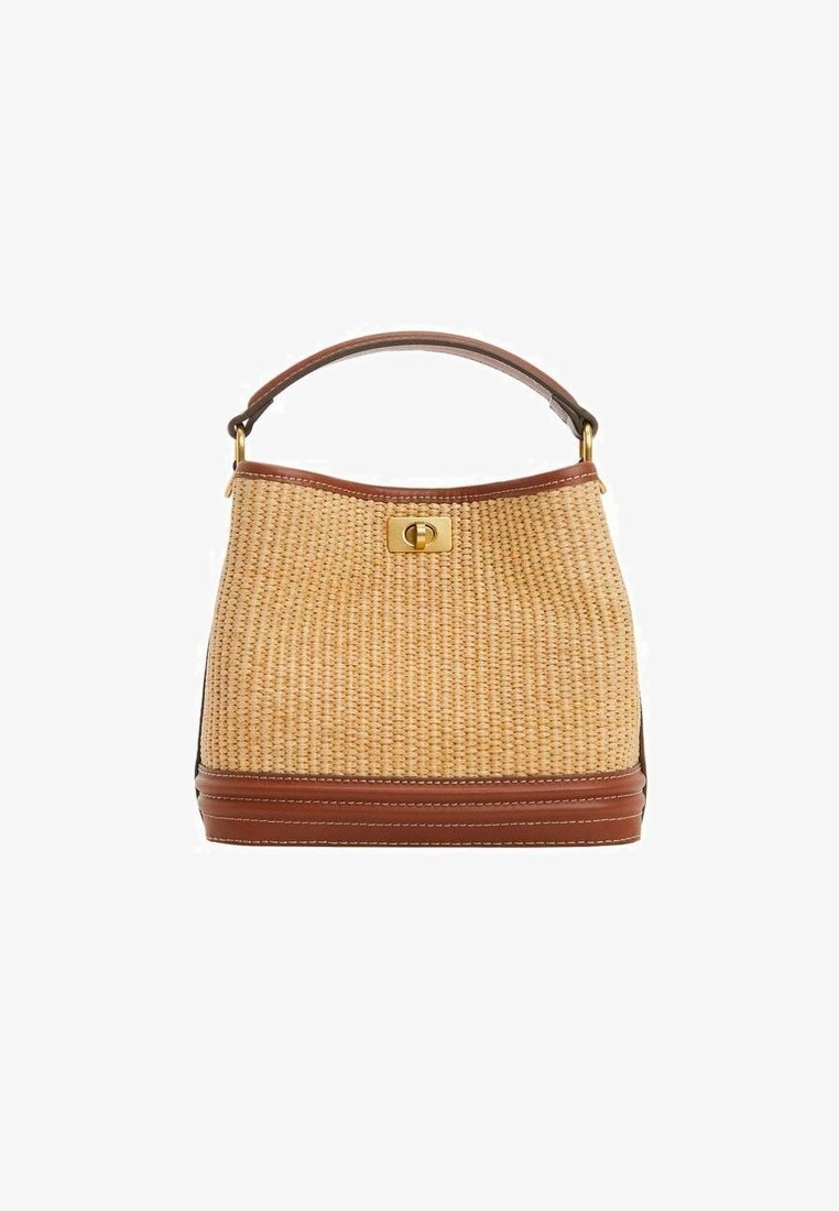 Sac à main en paille tissée avec garniture en cuir marron, poignée supérieure et fermeture à barillet dorée sur fond blanc.
