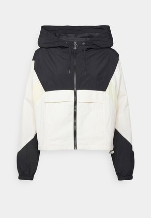 Schwarz-weiße Kapuzen-Windjacke mit Frontreißverschluss, Kordelzugkapuze, Reißverschluss-Zugring, elastischen Bündchen und großer Klappe an der Fronttasche.