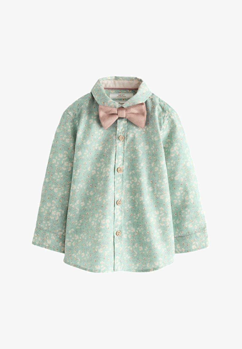 Mintgrünes Langarmshirt mit weißem Blumenmuster, ausgestattet mit einer Knopfleiste und einer hellpinkfarbene Fliege am Kragen.