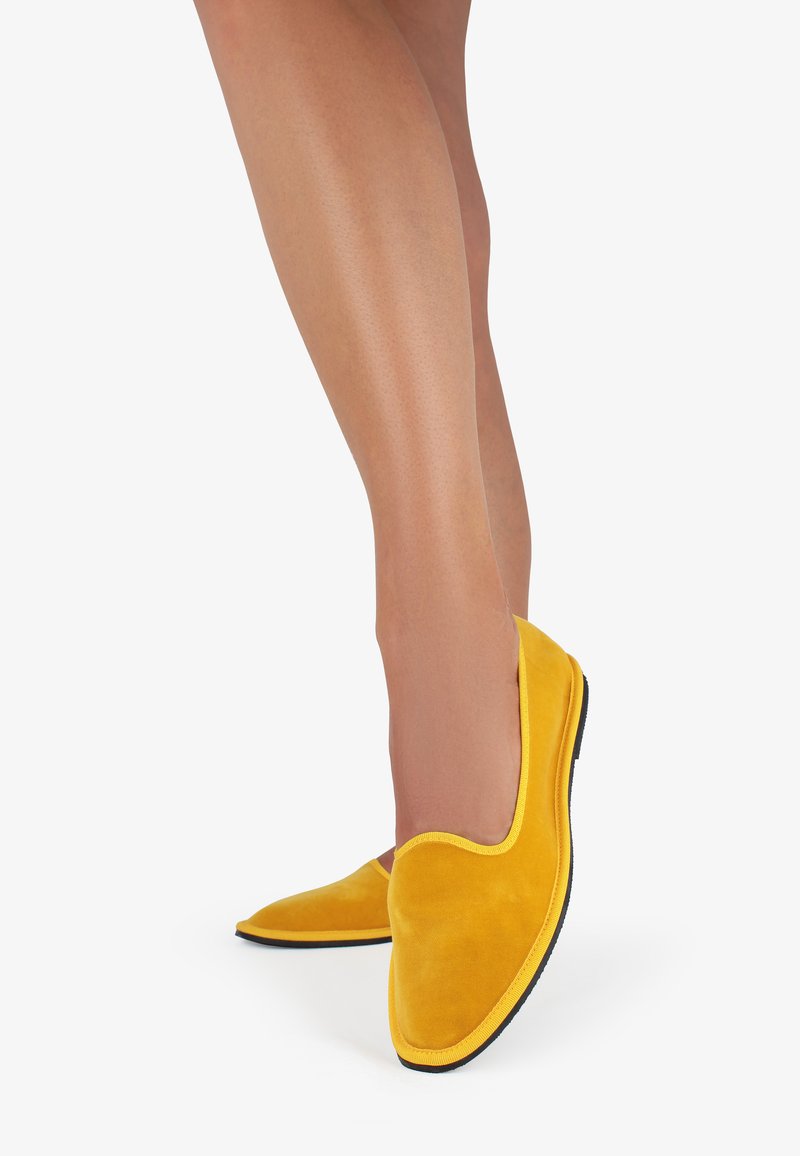 Scarpe slip-on in suede giallo con punta arrotondata e suola in gomma nera. Il design presenta una texture liscia e un bordo giallo a contrasto.