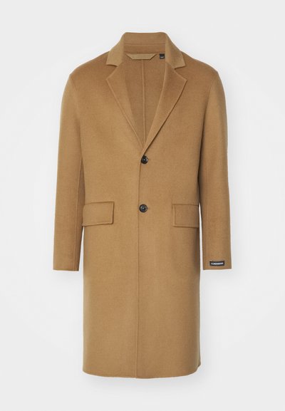 Lange camelkleurige wollen jas met een geknipte kraag, twee voorzakken en een enkele zwarte knoopsluiting. Heeft een zijlabel.