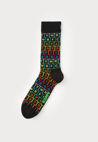 Schwarze Socken mit einem Gittermuster, das farbenfrohe Buchstaben in Blau, Grün, Gelb und Rot zeigt. Besonderer Text ist "HAPPY" in leuchtendem Grün.