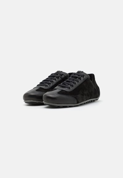 Black athletic shoes featuring a mix of smooth leather and suede, with a rounded toe, lace-up design, and textured rubber sole.