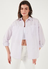 Striped button-up shirt in white with lavender vertical stripes, featuring two chest pockets and rolled sleeves, made from lightweight fabric.