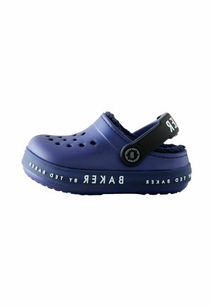 Zoccolo viola con fori di ventilazione, fodera morbida e una tracolla nera. Logo "BAKER" in bianco lungo il lato. Suola testurizzata per migliorare la trazione.