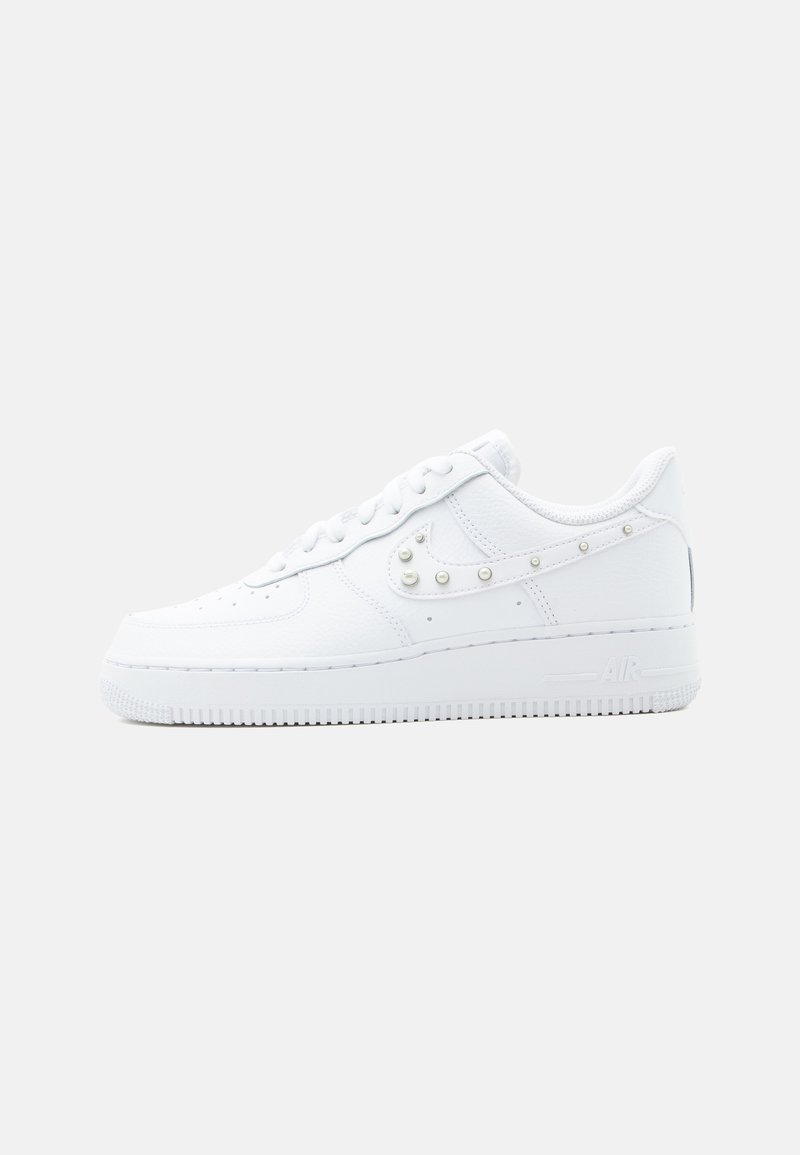 Λευκό αθλητικό παπούτσι Nike Air Force 1 με διακοσμητικό Swoosh με τρουκς και χοντρή σόλα, παρουσιάζεται σε απλό ανοιχτό γκρι φόντο.