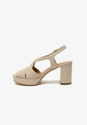 Sandalo beige con tacco alto, fascia anteriore intrecciata, punta aperta, cinturino alla caviglia slingback e tacco a blocco su sfondo bianco.
