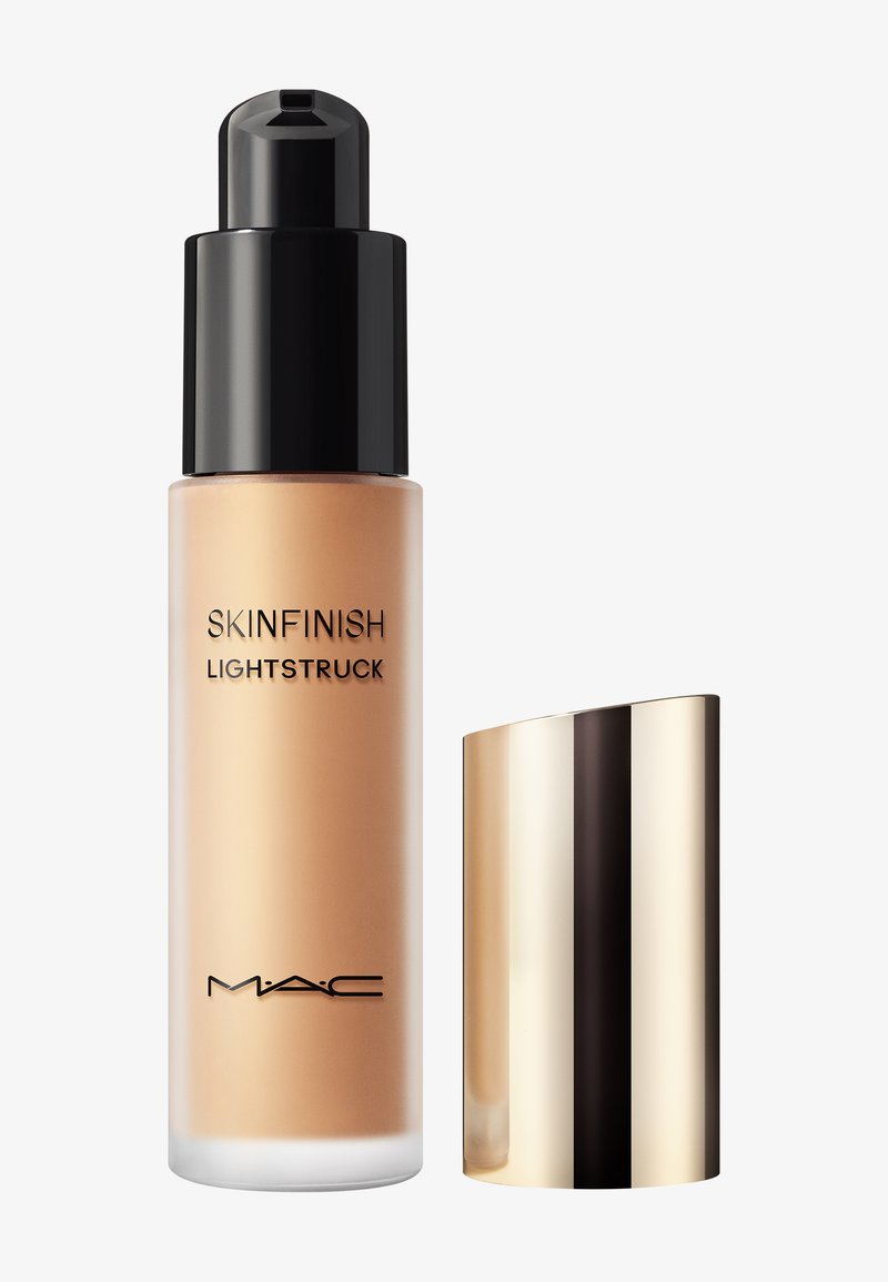 MAC Skinfinish Lightstruck foundationfles met zwarte pomp en losstaande glanzende gouden dop op witte achtergrond.
