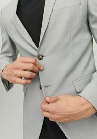 Light grey blazer with textured fabric, notch lapel, single button closure, and two front pockets. Button and stitch details visible.