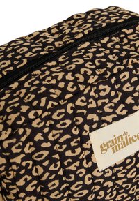 Trousse de maquillage en tissu matelassé arborant un motif léopard noir et beige, avec une fermeture éclair supérieure et une étiquette blanche avec un texte doré.