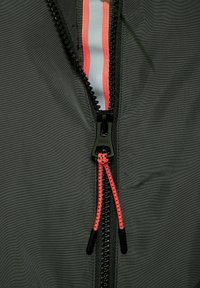 Zwarte jas met een gestructureerd oppervlak, voorzien van een ritstape in meerdere kleuren in roze en wit en een zwarte ritstrekker met het "CECIL" logo.