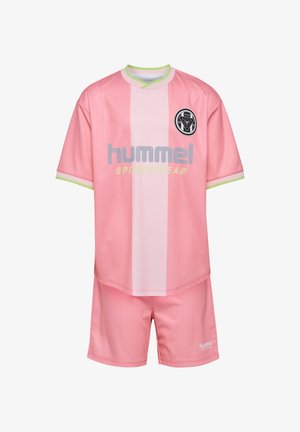 Dwoje dzieci w różowym ubraniu sportowym z logo "hummel", stojących obok siebie; dziewczynka ma różowe buty, chłopiec zielone, oboje w białych skarpetkach.