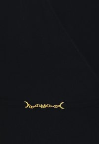 Prenda negra con una cadena metálica dorada que presenta acentos de luna creciente y un detalle central con la letra "M". Textura suave, diseño ajustado.