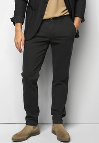 Zwarte op maat gemaakte broek met een slim fit, met een gladde textuur en zijzakken, gecombineerd met tan leren Chelsea boots.