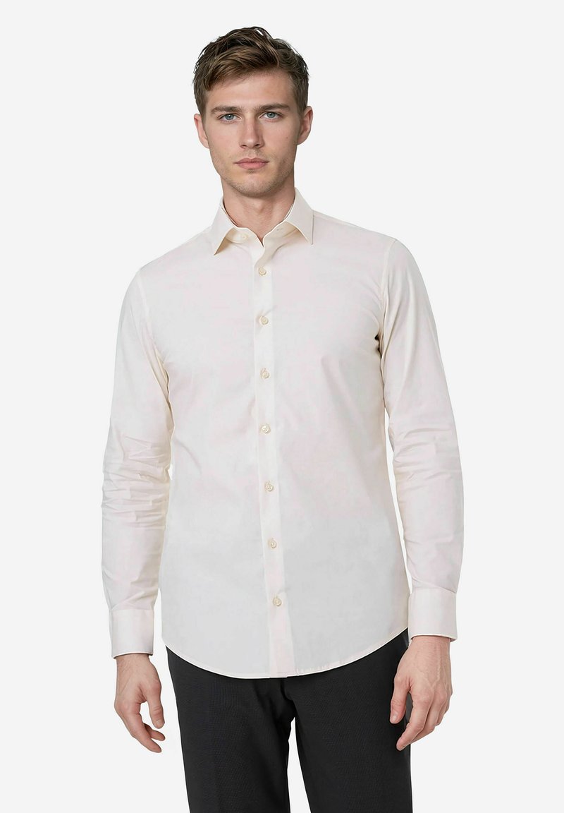 Lichtbeige langemouwen shirt met een spitse kraag, knoopsluiting aan de voorkant en een gladde textuur. De stof is licht getailleerd en heeft een knoopmanchetten.