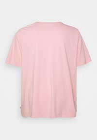 T-shirt à manches courtes rose clair en coton. Coupe col rond avec une texture douce et une petite étiquette logo sur la couture latérale.