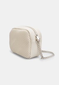 Piccola borsa a mano color crema con una texture intrecciata, cerniera argentata e tracolla a catena. Forma rettangolare con dettagli laterali.