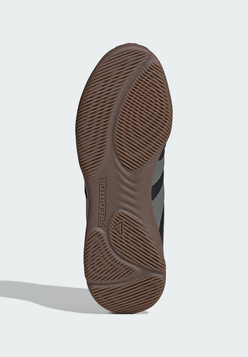 Schwarze und graue Sneaker-Sohle mit einer strukturierten Gumm Oberfläche, die wellenförmige Rillen und das "Predator"-Branding aufweist.