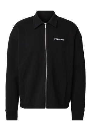 Musta vetoketjullinen takki, jossa on kaulus, etutaskut, pitkät hihat ja pieni valkoinen "PEGADOR"-logo vasemmassa rinnassa.