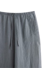 Šedé, lehké kalhoty s elastickým pasem, šňůrkou a bočními kapsami. Hladký povrch s uvolněným střihem.