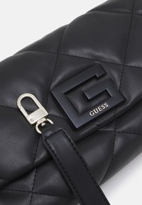 Mustikasta tikattu nahkalaukku, jossa on korostettu musta "G"-logo ja hopeiset metalliosat. Olkahihna on valmistettu sileästä nahasta.