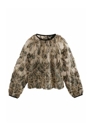 Kobieta w sukience z prześwitującej czarnej tkaniny ozdobionej misternymi złotymi i czarnymi cekinami w kształcie liści, odsłania szyję i długie brązowe włosy.