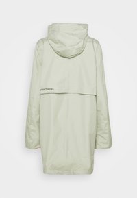 Ljusgrön vattentät jacka med huva, med en bakre axelklapp och logodetalj i svart. Rakt snitt, slät textur och minimalistisk design.