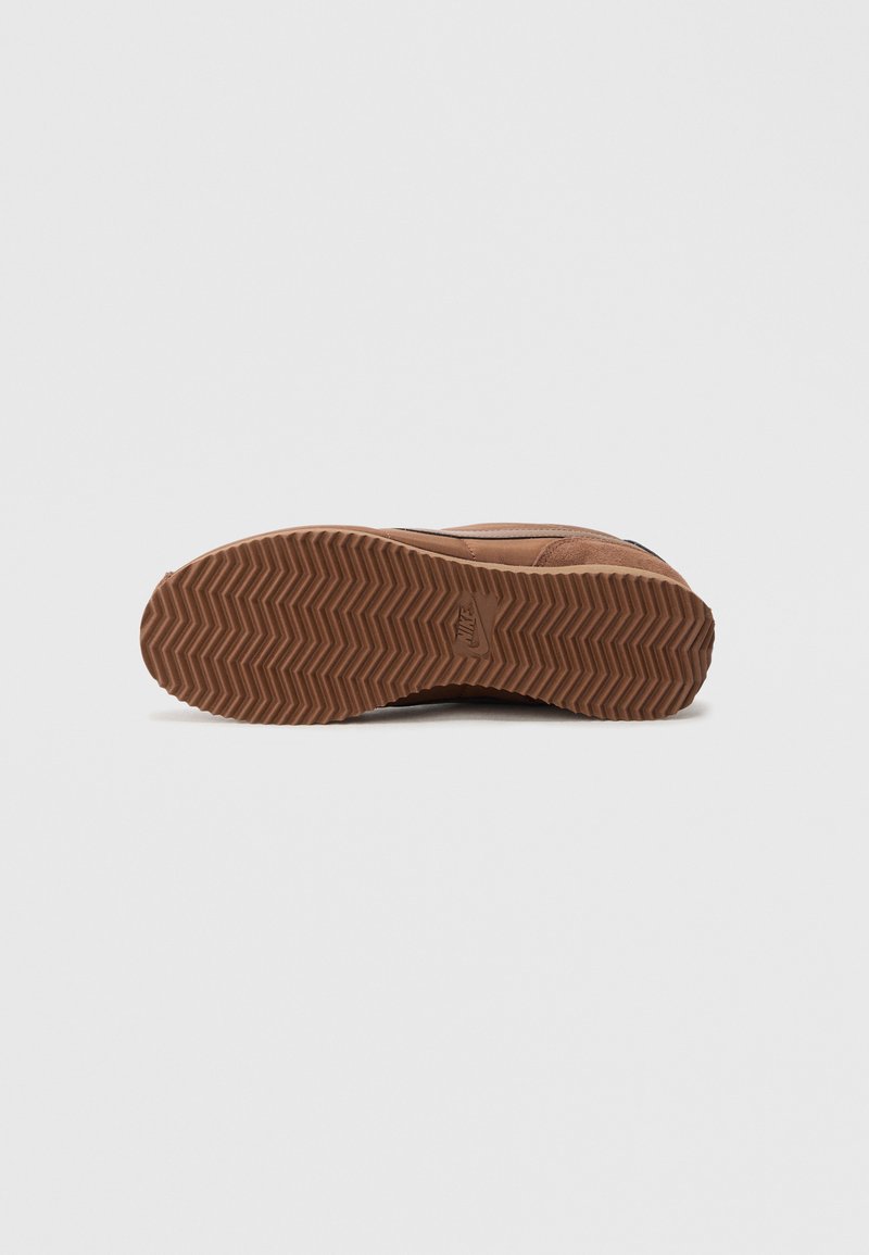 Brown sneaker sole with a textured, zigzag pattern. Features a soft, suede-like upper and a rubber outsole for traction.