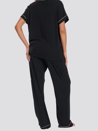 Svart pyjamasset som har en löst sittande kortärmad topp med vit kant och långt hår. Mjuk tyg och avslappnad silhuett.