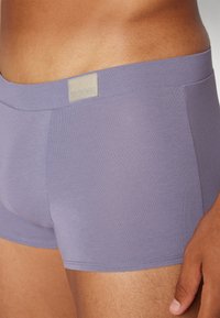Lila Baumwoll-Boxershorts mit einer weichen Textur, ausgestattet mit einem Sloggi-Logoetikett am Bund und einem figurbetonten Design.