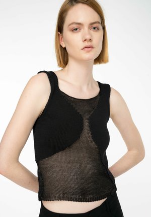 Débardeur en tricot noir avec une insertion en maille texturée et une forme ajustée. Accentué par un ourlet brut et des bretelles larges.