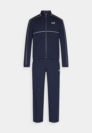 Marineblauer Trainingsanzug aus weichem Stoff, bestehend aus einer Reißverschlussjacke mit weißen Paspeln und passenden Hosen. Beide Teile sind mit Logoakzenten versehen.