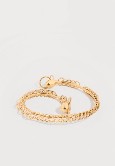 Βραχιόλι ανοιχτού τύπου με επίστρωση χρυσού τόνου, με περίτεχνο σχέδιο από συρματόπλεγμα και λείες διακοσμήσεις σε σχήμα σταγόνας σε λευκό φόντο.