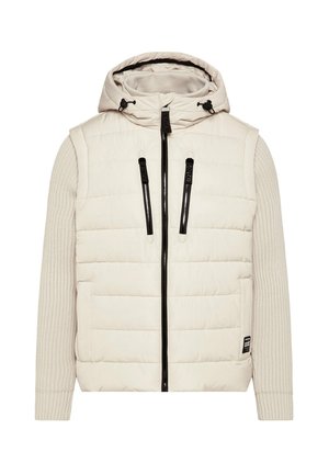 Puffjacke in hellbeige mit gesteppter Struktur, gerippten beigen Ärmeln, schwarzem Reißverschluss, verstellbare Kapuze und Seitentaschen.