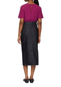 Fuchsia top met korte mouwen en knoopdetail op de rug, gecombineerd met een donkerdenim hoge taille rok met steekzakken en een knielange snit.