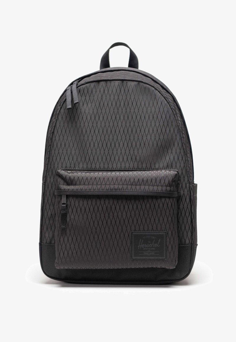 Sac à dos noir à motif losange avec poche avant zippée et poignée supérieure, avec un patch de marque rectangulaire sur la poche avant inférieure.