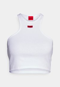 Vit ribbad crop top med hög krage och röda "HUGO" logotyp-patchar på framsidan och inuti bakre kragen.