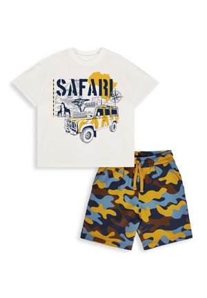 Chemise blanche à manches courtes avec imprimé véhicule de safari, carte de l'Afrique et animaux, associée à un short camouflage bleu, marron et jaune.