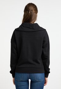 Zwarte sweatshirt met capuchon, gemaakt van zachte stof. Heeft een losse pasvorm, ribbelmanchetten en -zoom, met een naadloos achterontwerp.