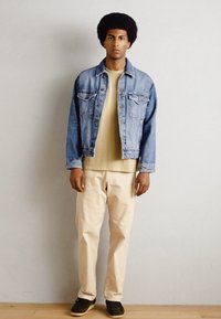 Vaatekaappi: vaaleansininen farkkutakki, beige t-paita, vaaleat housut ja tummat lenkkarit. Yksinkertainen muotoilu, rento istuvuus ja tasaiset värit, joissa on minimaalista yksityiskohtaisuutta.