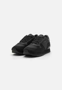 Sorte sneakers med en kombination af tekstureret mesh og glat ruskind, med snørebåndsdesign og diskret branding på siden.