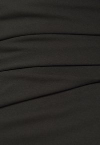 Tissu noir avec une surface texturée, présentant des plis doux et drapés avec un léger stretch. L'ensemble du design est lisse et continu.
