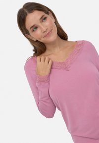 Top de manga larga rosa con un corte relajado y detalles de encaje en el escote en V y los puños, confeccionado con una suave tela texturizada.