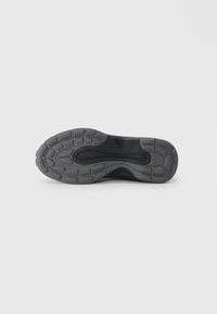 Talpa de pantof sport negru, cu cauciuc gri texturat și un design de tip model pentru aderență și stabilitate. Designul concav îmbunătățește flexibilitatea.