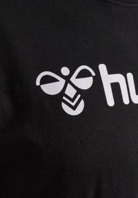 Zwarte katoen t-shirt met een opvallend wit grafisch ontwerp, dat lijkt op een gestileerde bij met geometrische accenten en het woord "hub."