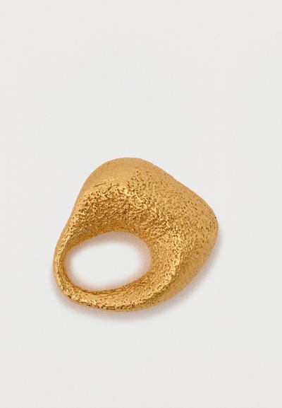 Zelta tonis gredzens ar teksturētu, organisku formu un atvērto joslu, kas izceļas ar gludu, spīdīgu virsmu un nedaudz neregulāru formu.